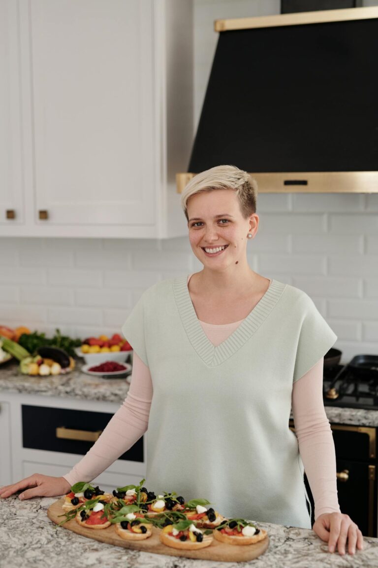 Smiling woman prepares healthy appetizers in a modern kitchen setting.